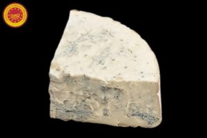 Part de gorgonzola crémeux à pâte persillée sur une planche en bois avec noix et pain de campagne