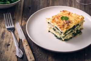 Part de lasagnes aux épinards et au chèvre gratinées dans un plat