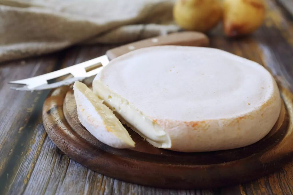 Meule de reblochon au lait cru posée sur une planche en bois, fromage de Savoie