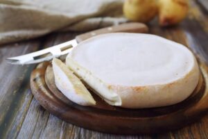 Meule de reblochon au lait cru posée sur une planche en bois, fromage de Savoie